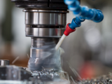 Milling machine cutting a metal part with coolant flowing over the rotating tool